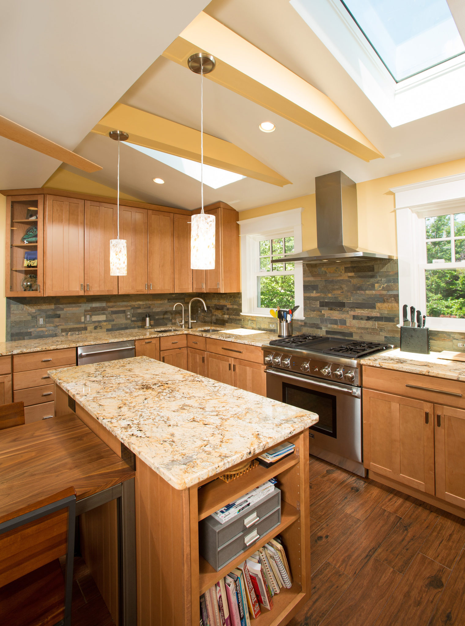 A kitchen featuring wooden cabinets, a countertop, and various home appliances. The space includes a sink, stove, and oven, with hardwood flooring and ceiling beams enhancing the interior design.