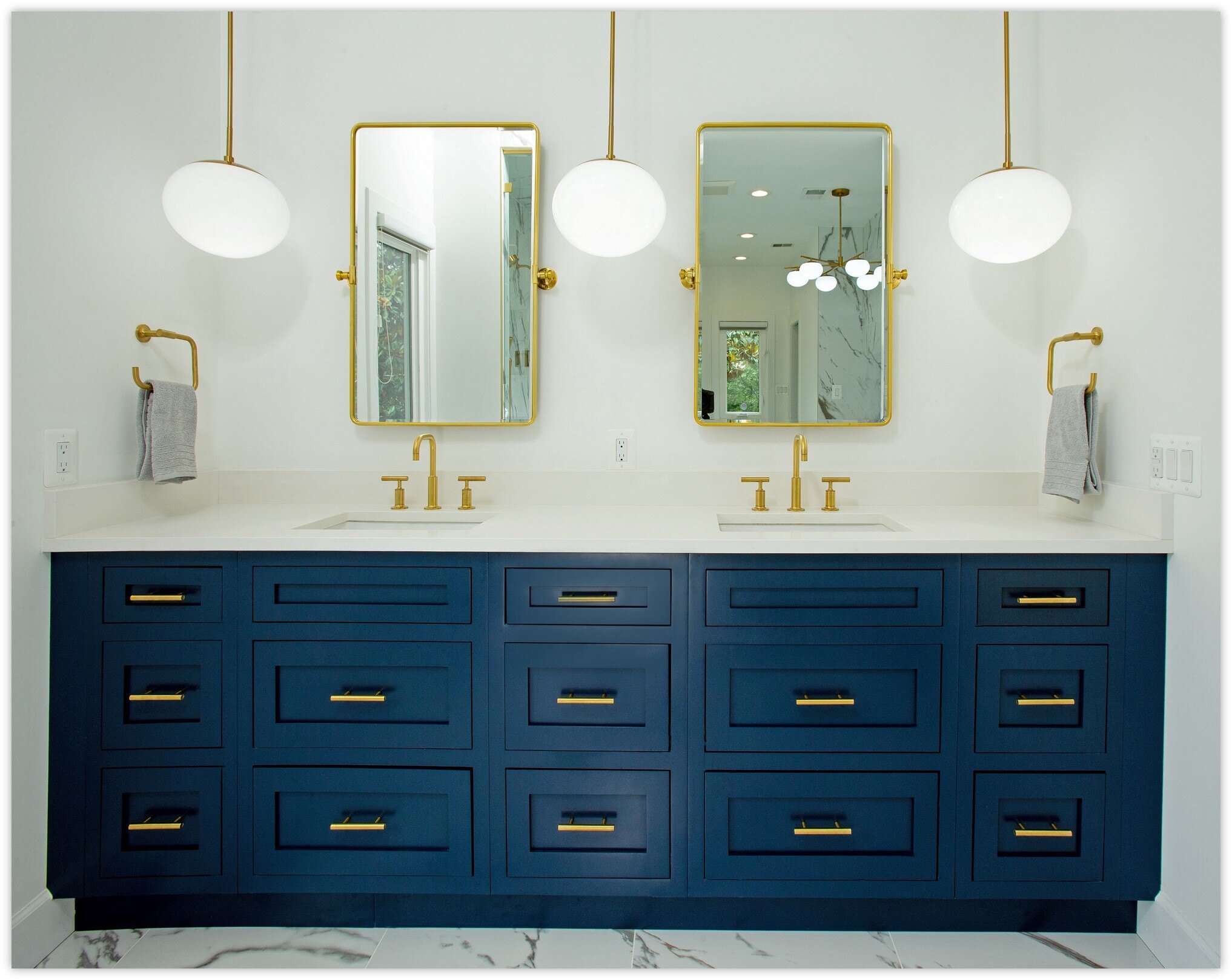 A bathroom emerges from a recent home remodel, showcasing a dark vanity with a white countertop, complemented by a sleek stainless steel faucet. Two framed pictures adorn the wall above the toilet, while a sliding barn door discreetly reveals a shower adorned with pristine white tiles.